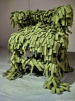 Front-left angle photo showing the green wool blanket strips tied over the child's captain chair with textured fringe all over the frame.