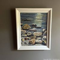 Frontal view of the framed oil painting displaying the rocky shoreline and shimmering lake under late afternoon sun.