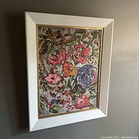 Framed floral oil painting hanging on a wall, shows full front view of artwork and frame.