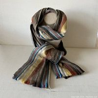 Full view of the scarf knotted and displayed on a stand showing the color stripes and overall length.