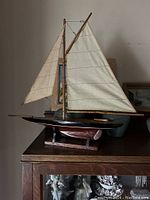 Front left side view of the sailing ship model showing sails, wooden hull and stand.