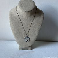 Full view of the necklace displayed on a beige bust, showing the Yin & Yang pendant and chain.