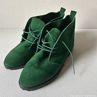Front angle view of the green suede boots showing vibrant color and laces tied.