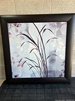 Framed square painting showing botanical theme with purple leaves and grass-like stems on an abstract muted background.