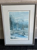 Framed winter landscape painting showing pond, trees, grass, and bird in flight.