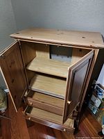 Photo of wooden cabinet with open doors showing adjustable shelves and drawers inside