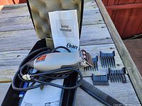 Oster hair clippers with power cord, four clipper attachments, black comb, service information booklet inside black hard carrying case with foam padding