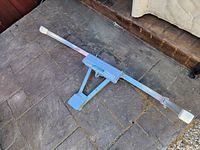 Photo of a 40 inch metal extension ladder part with a metal bracket and white plastic end caps lying on a stone surface.