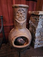 Front view of terracotta outdoor fireplace showing Texas-themed raised designs and metal base.