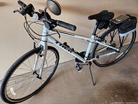 Photo showing the Trek FX Sport bicycle with a white frame and black accents, handlebars with grips, front headlight, rear rack with storage bag, and cycle computer mounted on the handlebar.
