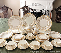 Overview of full set displayed on table: stacks of large and small plates, cups, saucers, sugar bowl, creamer and tureen