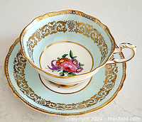 Porcelain teacup and one saucer showing gold filigree and floral design inside cup and on saucer.