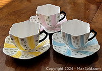Set of the three cups and saucers on wooden table showing colors yellow, pink and blue with circular accents