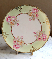 Full view of the round plate showing floral design on light green background with gold details.