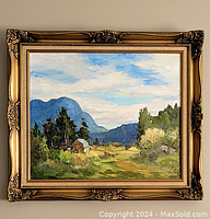 Framed oil painting showing a mountain landscape with trees, barn, and sky, photographed from front.