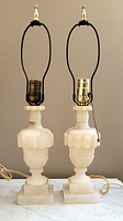 Pair of two alabaster table lamps shown from front with brass sockets and no shades.