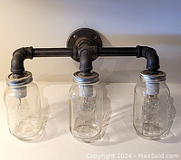 Front view of the 3-light plumbing pipe fixture with mason jar covers, showing industrial style and detailing.