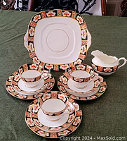 Full view of the partial set including three teacups with saucers, a creamer and a square serving plate.