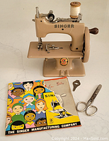 Front view of Singer Sewhandy toy sewing machine with booklet, scissors and tool laid out