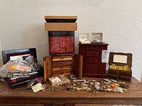 Wide shot of all jewelry boxes, loose costume jewelry pieces, and pins spread on a table.