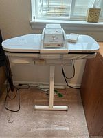 Front view of Euro-Pro steam press on pedestal stand with foot pedal on pressing board.