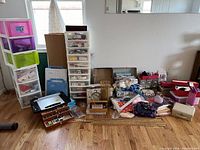 Overview photo showing color-coded plastic storage tubs and drawers with lots of assorted sewing supplies spread on the floor.