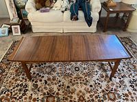 Top-down view of rectangular walnut veneer tabletop on patterned rug