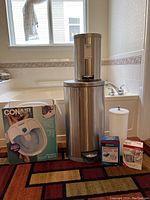 Photo showing all items in lot including trash cans, foot spa, blood pressure monitors, and metal container dispenser