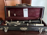 Vintage clarinet assembled inside the red velvet lined black hard case showing barrel and bell sections.