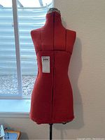 Photo of the red fabric torso of the vintage dressmaker's form from front, showing height to chest area.