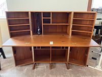 Front view of desk opened, showing three fold-down panels and upper shelving