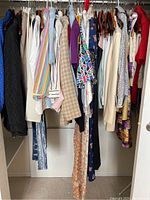 Full closet shot showing varied women's clothing hung on hangers, multiple tops dresses and jackets in assorted colors and patterns