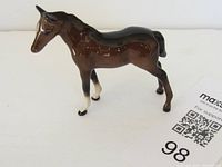 Side view of glossy brown Beswick horse figurine on white background with MaxSold card