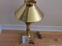 Full view of the vintage brass lamp showing its conical shade, square decorative base, and attached power cord.