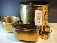 Four vintage brass planters collectively shown on a white surface with black background, highlighting the varying sizes and shapes.