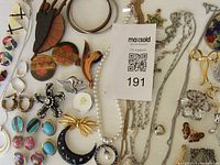 Overview of vintage costume jewelry including necklaces, earrings, brooches, and bracelets laid out on a white surface.