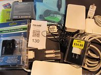 Photo showing various electronics including unopened USB power adapters, microSD cards, cables, and chargers arranged on a surface.