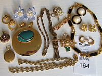 Full view of all jewelry items: several necklaces, earrings, brooches, and pendants arranged on white background with auction tag