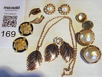 Top view showing all jewelry pieces arranged closely: 3 pairs of clip-on earrings and 1 necklace with leaf pendant.