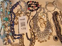 Full display of assorted vintage costume jewelry pieces on a table including necklaces, earrings, and bracelets with a MaxSold tag.