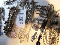 Photo showing diverse vintage costume jewelry pieces including necklaces, a brooch, and bracelets arranged on a flat surface.