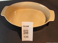 Front view of oval baking dish showing black exterior and ivory interior