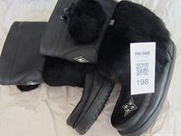 Pair of black leather Manitoba Mukluk boots with fur collars and beaded decoration, side view.