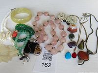 Full lot showing assortment of vintage costume jewelry including bracelets, necklaces and pendants of natural stones.
