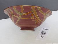 Side view of a large pottery bowl showing reddish base color with yellow-orange crackled vine decoration.