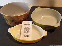 Three Pyrex casserole dishes sized small to large with distinctive vintage patterns and colors