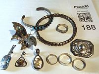 Overview of the jewelry lot including bracelets, rings, pendants, and brooch. Shows condition and variety.