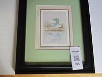 Full view of the framed print showing the black frame, green matting, and the illustration of the loon bird.
