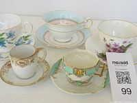 Photo showing all five vintage and antique teacups with matching saucers grouped together, highlighting various floral designs and gold trims.