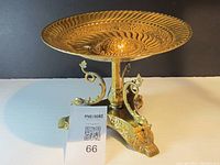 Full view of vintage brass centerpiece bowl showing top embossed circular pattern and pedestal stand with decorative scrolls and base with lion paw feet.